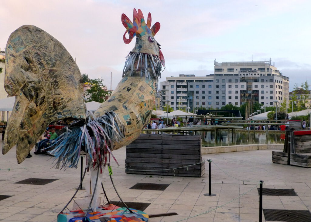 Praca Martim Moniz mit der nicht zu übersehenden Skulptur eines Huhns, die zum Teil aus Zeitungen besteht. Im Hintergrund das Hotel Mundial, unsere Unterkunft